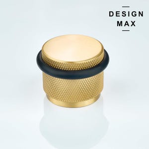May include: A gold doorstop with a black rubber stopper. The doorstop has a textured design.