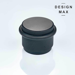 May include: A black doorstop with a silver top and a textured design. The doorstop is made of metal and has a rubber ring around the top.