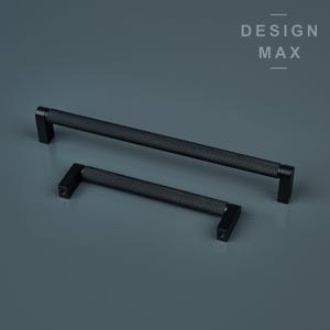 Könnte beinhalten: Zwei schwarze Schrankgriffe mit einem strukturierten Rautenmuster. Ein Griff ist länger als der andere. Die Griffe haben an jedem Ende eine rechteckige Form. Der Text "DESIGN MAX" befindet sich in der oberen rechten Ecke.