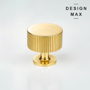 Peut inclure: Bouton de porte en or avec un motif strié. Le bouton a un dessus rond et une base cylindrique.