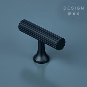 Può includere: Pomo per armadio a forma di T in metallo nero con un design scanalato. DESIGN MAX è stampato in bianco su uno sfondo grigio.