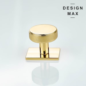 Puede incluir: Pomo de puerta dorado con base cuadrada y parte superior redonda texturizada. El pomo tiene un patrón de diamante en la parte superior.