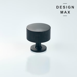 Puede incluir: Pomo de armario negro con diseño estriado y base redonda. DESIGN MAX.