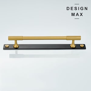 May include: Gold metal bar handle with black metal mounting plate and screws.  DESIGN MAX is printed on the white background.