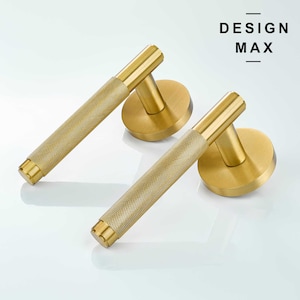 May include: Two gold door handles with a textured design. The handles are made of metal and have a round base.