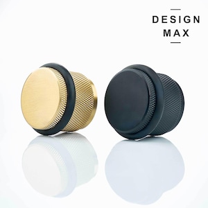 May include: Two door stops, one gold and one black, with a rubber seal. The door stops have a textured design.