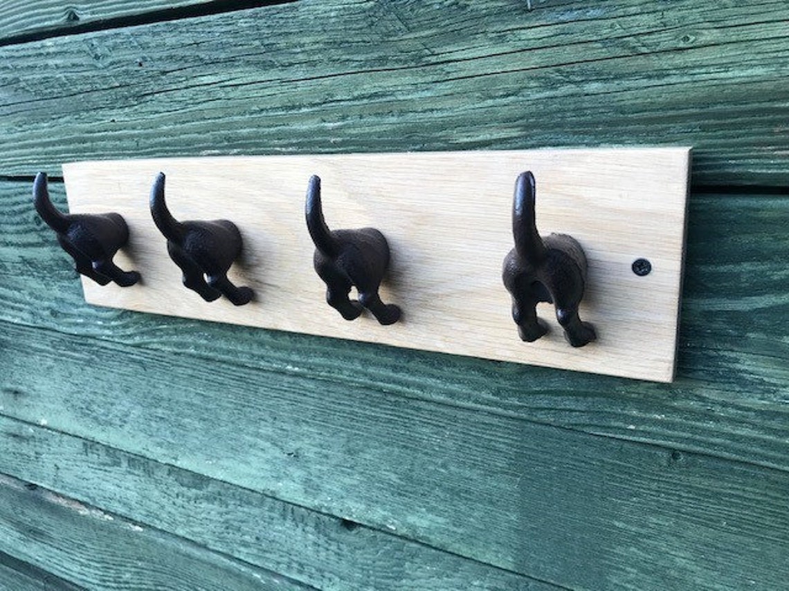 Cast iron dog tail hooks on a waxed oak plinth Etsy.de