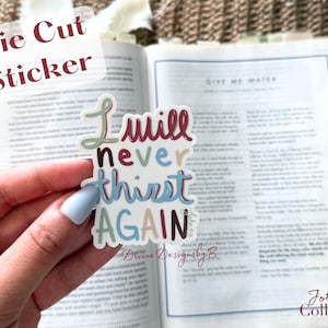 May include: A die-cut sticker with the words "I will never thirst AGAIN" in a colorful, handwritten font. The sticker is held in front of an open book. The text "John 4:14 Collection" is also visible.