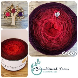 May include: A skein of ombre yarn in shades of purple, red and orange. The yarn is wound into a ball and labelled "Bramblewood Yarns" with the code "CA008".