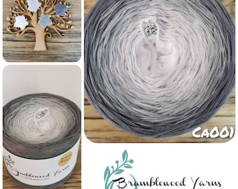 May include: A skein of gray ombre yarn with a white center. The yarn is labeled "Bramblewood Yarns Gradient ombre cakes" and has the code "CA001" printed on the label.