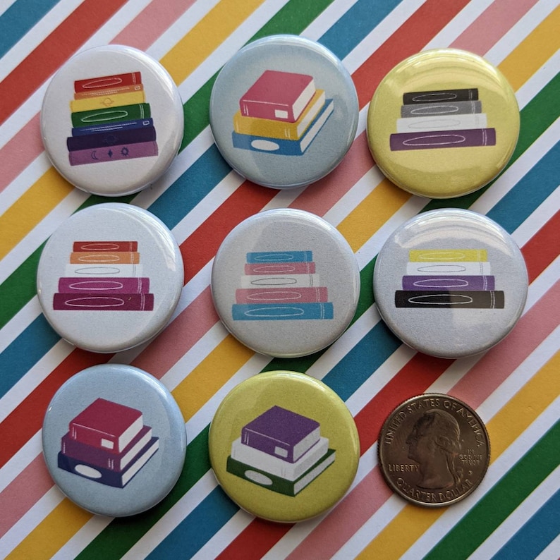 Op de afbeelding: Tien kleurrijke ronde knoppen met stapels boeken erop. De knoppen zijn gerangschikt in twee rijen van vijf. De knoppen zijn allemaal in verschillende kleuren, waaronder rood, oranje, geel, groen, blauw, paars, roze en wit. De boeken op de knoppen zijn allemaal in verschillende kleuren en maten.