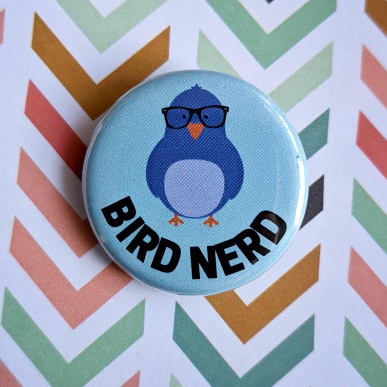 Pode incluir: Um p&aacute;ssaro azul usando &oacute;culos com o texto "Bird Nerd" em um fundo azul claro.