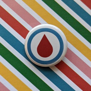 May include: A white button with a blue circle and a red drop inside. The button has a white background and a blue border.