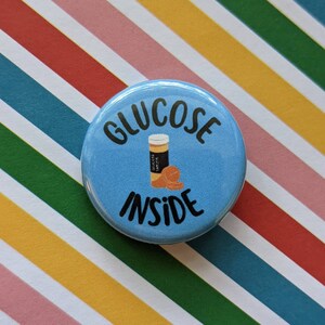 May include: A blue button with the text "GLUCOSE INSIDE" in black. A cartoon illustration of a bottle of glucose tablets is inside the text.