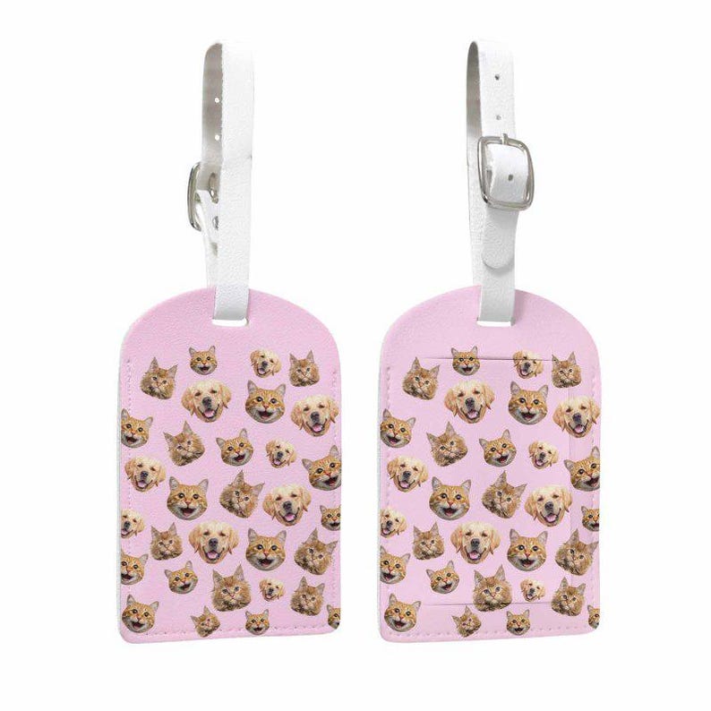 May include: Two pink luggage tags decorated with a repeating pattern of cat and dog faces. Each tag has a white strap and a silver buckle. These travel tags are designed with a fun pet theme.