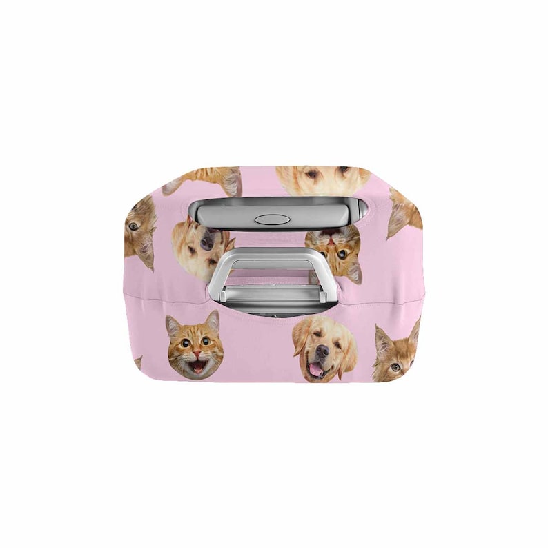 May include: A pink suitcase cover with a repeating pattern of cat and dog faces. The cover has cutouts for the handle and is designed to fit over a suitcase. The animal faces are in shades of orange, brown, and gold.