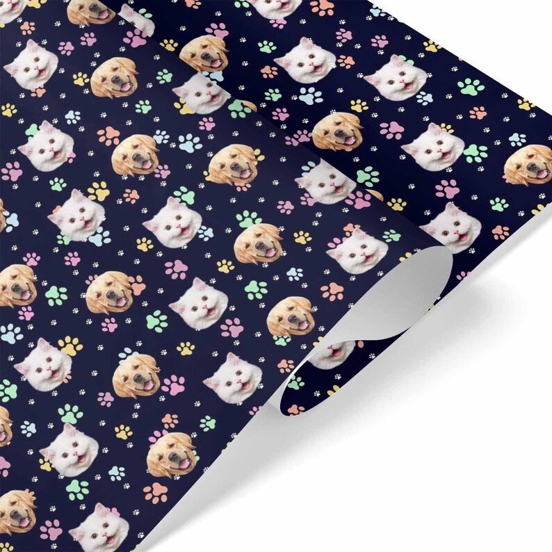 May include: A blue wrapping paper with a repeating pattern of cat and dog faces and paw prints in pink, yellow, and green.