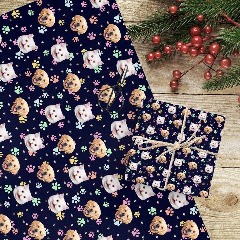 May include: A blue wrapping paper with a repeating pattern of paw prints, cats, and dogs. The cats and dogs have different colored collars. The wrapping paper is shown wrapped around a gift box.