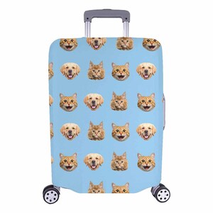 May include: A light blue suitcase cover with a repeating pattern of smiling cat and dog faces. The luggage has a retractable handle and wheels, designed for travel. The cover is made of a durable material.