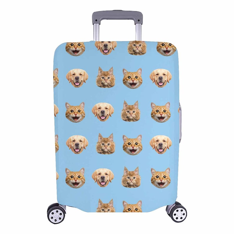 May include: A light blue suitcase cover with a repeating pattern of smiling cat and dog faces. The luggage has a retractable handle and wheels, designed for travel. The cover is made of a durable material.