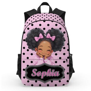 May include: Pink backpack with black polka dots and black trim. The front features a smiling cartoon girl with curly hair and pink bows. The name "Sophia" is displayed in a black and white frame.