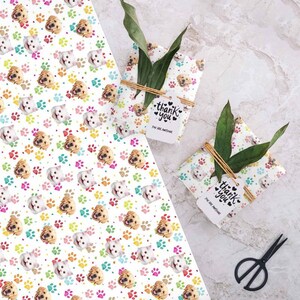 May include: Two white gift boxes wrapped in white wrapping paper with a repeating pattern of colorful paw prints and dog and cat faces. The boxes are tied with twine and have a white gift tag attached to each that says "Thank you, You are awesome".