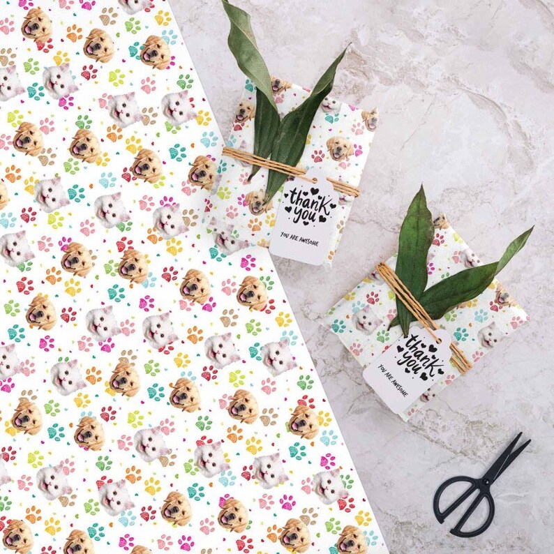 May include: Two white gift boxes wrapped in white wrapping paper with a repeating pattern of colorful paw prints and dog and cat faces. The boxes are tied with twine and have a white gift tag attached to each that says "Thank you, You are awesome".