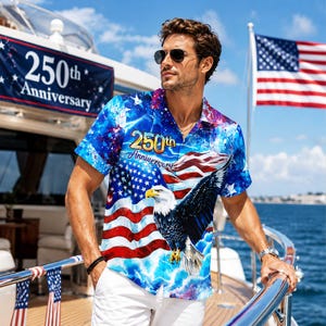 Puede incluir: Una camisa de manga corta con botones que presenta un estampado vibrante de la bandera estadounidense, un águila calva en vuelo y el texto 250th Anniversary. El diseño incorpora colores azul, rojo y blanco con un fondo de nubes celestiales.