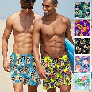 May include: Two people wearing swim trunks with a pattern of faces. The swim trunks are blue and yellow with a tropical leaf design. The text "28. تموز. MCMXCII" is visible on the left side of the image.