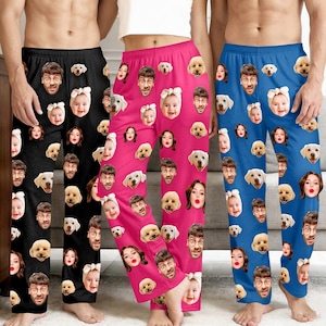 Könnte beinhalten: Drei Schlafanzughosen in Schwarz, Pink und Blau, jede bedeckt mit einem sich wiederholenden Muster aus Gesichtern und Hundegesichtern. Die Schlafanzughosen sind aus einem weichen Material und haben eine lockere Passform.