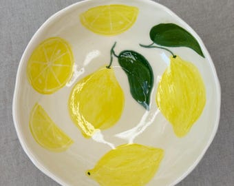 May include: White ceramic bowl with a hand-painted lemon design. The bowl features whole lemons, lemon slices, and green leaves.