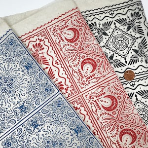 Könnte beinhalten: Drei Stoffmuster mit verschiedenen Bandanamustern. Das erste Muster hat ein blaues Paisley-Muster, das zweite ein rot-weißes Muster mit Halbmonden und floralen Designs und das dritte ein schwarz-weißes Muster mit einem Vogeldesign.