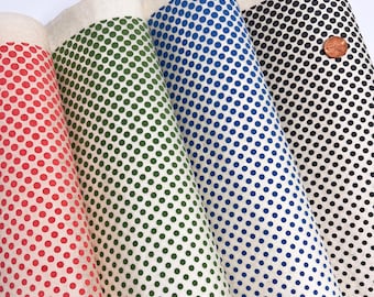May include: Four rolls of off-white fabric featuring repeating polka dot patterns in red, green, blue, and black. A small, round, copper-colored metal button is placed on the black polka dot fabric roll for scale.