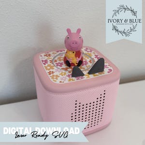 Puede incluir: Un reproductor de audio rosa con un diseño floral en la parte superior, con una figura de Peppa Pig. El reproductor tiene una rejilla de altavoz y el texto "DIGITAL DOWNLOAD Laser Ready SVG" en una pancarta.