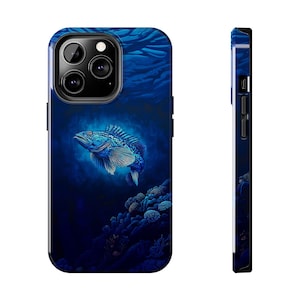 May include: A blue phone case featuring a detailed illustration of a fish swimming underwater. The design includes coral and a dark blue background, creating a deep-sea aesthetic. The case is shown from the front and side.