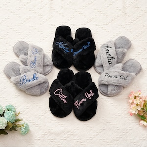 May include: Six pairs of fluffy black and grey slippers with the words "Flower Girl" and names embroidered on them.