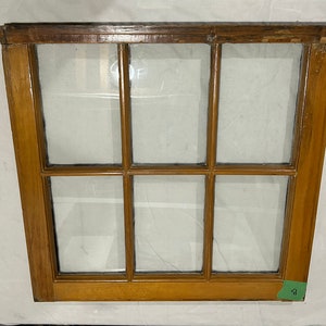 May include: A wooden window frame with nine panes of glass. The frame is a light brown colour and the glass is clear. The window is in good condition and has no visible damage.