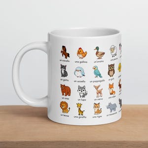 Puede incluir: Taza de cerámica blanca con ilustraciones de dibujos animados de animales, cada uno con una palabra italiana. Los animales incluyen un caballo, una gallina, un pato, un gato, un pájaro, un loro, un oso, un lobo, un ciervo, un león, una jirafa y un tigre.