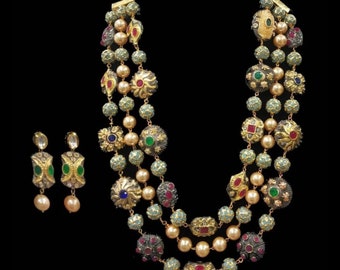 May include: A three-strand necklace and matching earrings set. The necklace features gold-toned metal, teal beads, and faux pearls, with colourful gemstone accents. The earrings have a similar design with green, red, and clear stones.