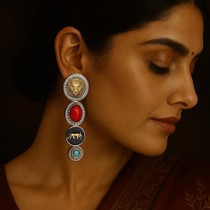 Puede incluir: Pendientes colgantes elegantes con un león dorado, una piedra roja, un tigre dorado y una piedra turquesa, todo engastado en plata con un borde de diamantes. Los pendientes se muestran en una oreja sobre un fondo oscuro.