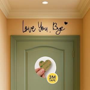 May include: Black script text reading "Love You, Bye" with a heart symbol above a green door. A heart-shaped adhesive pad with the text "3M 300LSE" is shown on the door, with a "3M TAPE" sticker below.