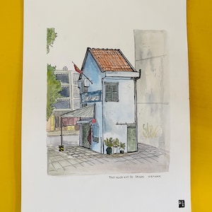 Può includere: Acquerello di un piccolo edificio azzurro con tetto di tegole rosse. L'edificio ha una piccola tenda da sole e una finestra con persiane scure. Il testo "TINY HOUSE NO.03 SAIGON VIETNAM" è in basso.
