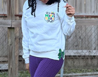 May include: White sweatshirt with a green, yellow, and purple Mardi Gras design that says "It's Mardi Gras Y'all!"  The sweatshirt has a green and gold bow on the side.