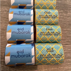 May include: A set of six blue and gold gift boxes with the text "eid mubarak" on each box. The boxes have different patterns, including geometric shapes and a traditional Islamic design.