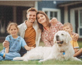 Op de afbeelding: Een gezin van vier, waaronder twee kinderen, zit op een groen gazon met een witte hond. De volwassenen dragen casual kleding, terwijl de kinderen een overall en een geel shirt dragen. De hond ligt op het gras met zijn kop op de schoot van een van de volwassenen.