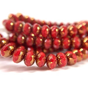 May include: Close-up of red faceted beads with gold accents. The beads are strung together, showcasing their intricate design and color. The beads are likely for jewelry making.