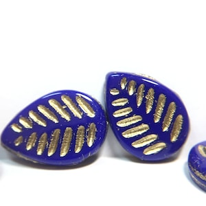 May include: Three blue glass beads with gold leaf designs. The beads are teardrop shaped and have a glossy finish.