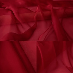 Pode incluir: Um close-up de um tecido transparente vermelho escuro. O tecido é macio e fluido, com uma textura delicada.