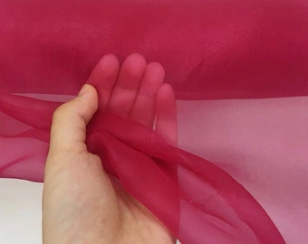 May include: A roll of sheer, translucent fabric in a deep crimson red color. The fabric is soft and delicate, with a slight sheen.