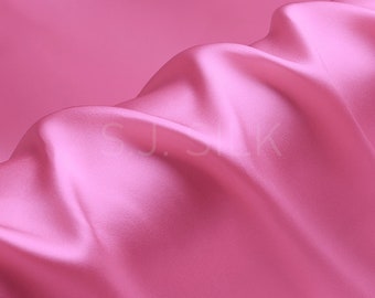 May include: A smooth, pink satin fabric with a soft, flowing texture. The fabric is draped and folded, creating a luxurious and elegant look.